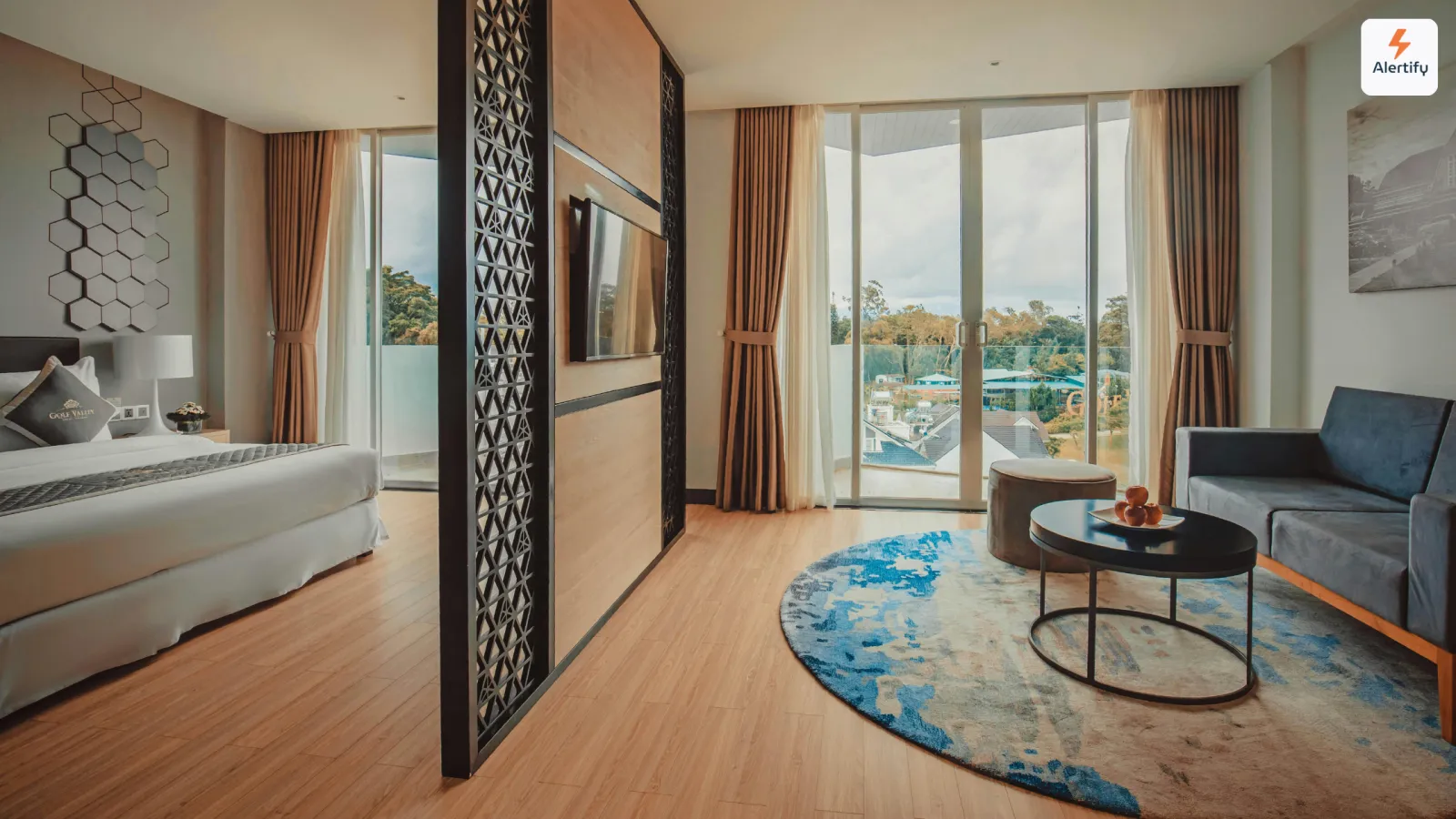 Apartament modern de închiriere pe termen scurt, cu pat făcut, canapea albastră și ferestre de la podea la tavan spre balcon
