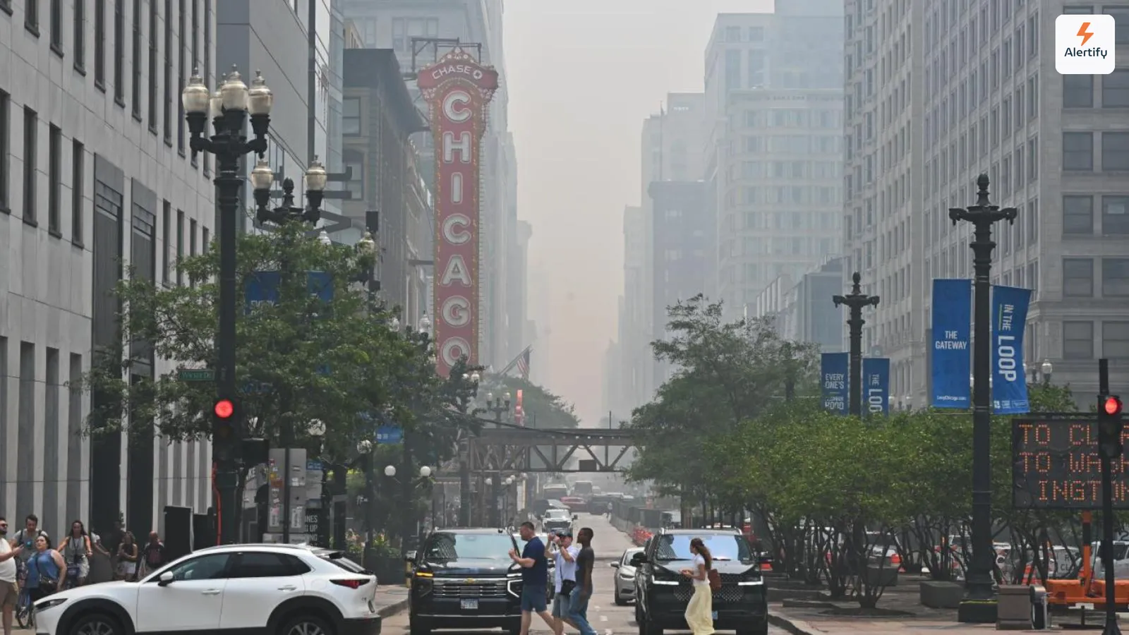 Ceață de fum de incendii care înghite clădirile de pe o stradă din Chicago, cu firma iluminată a Chicago Theatre în prim-plan.