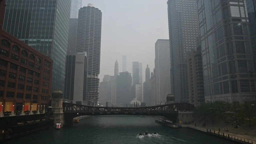 Linia orizontului și râul din Chicago reduse la siluete gri de ceața densă de fum.