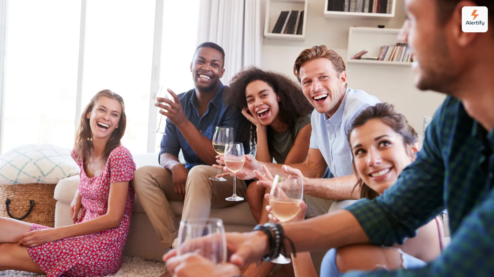Grup de prieteni râzând cu pahare de vin într-un living dintr-o închiriere de vacanță